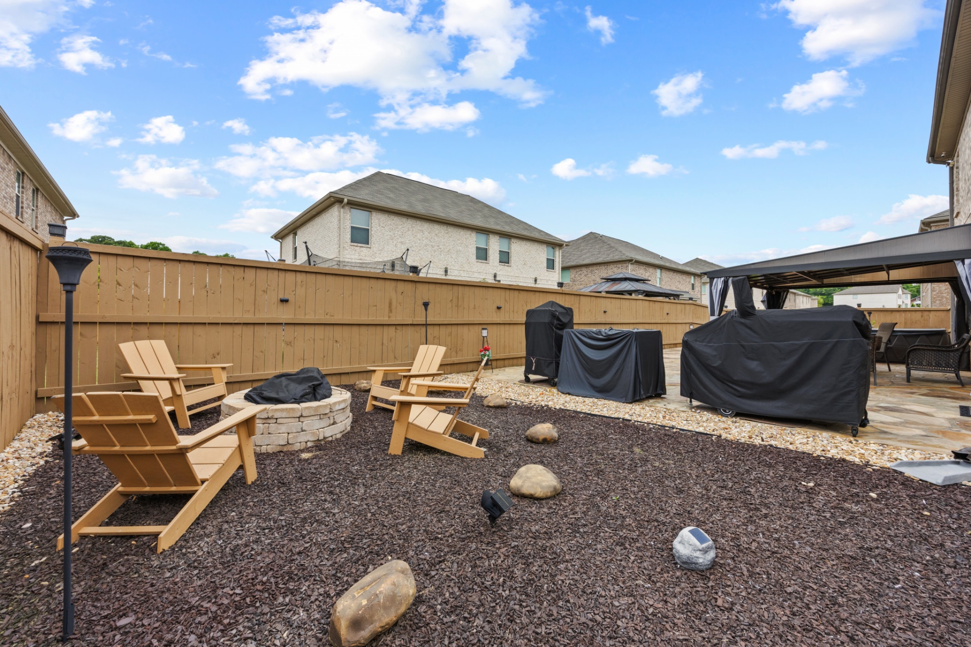 Backyard firepit lounge with adirondack chairs and grill area