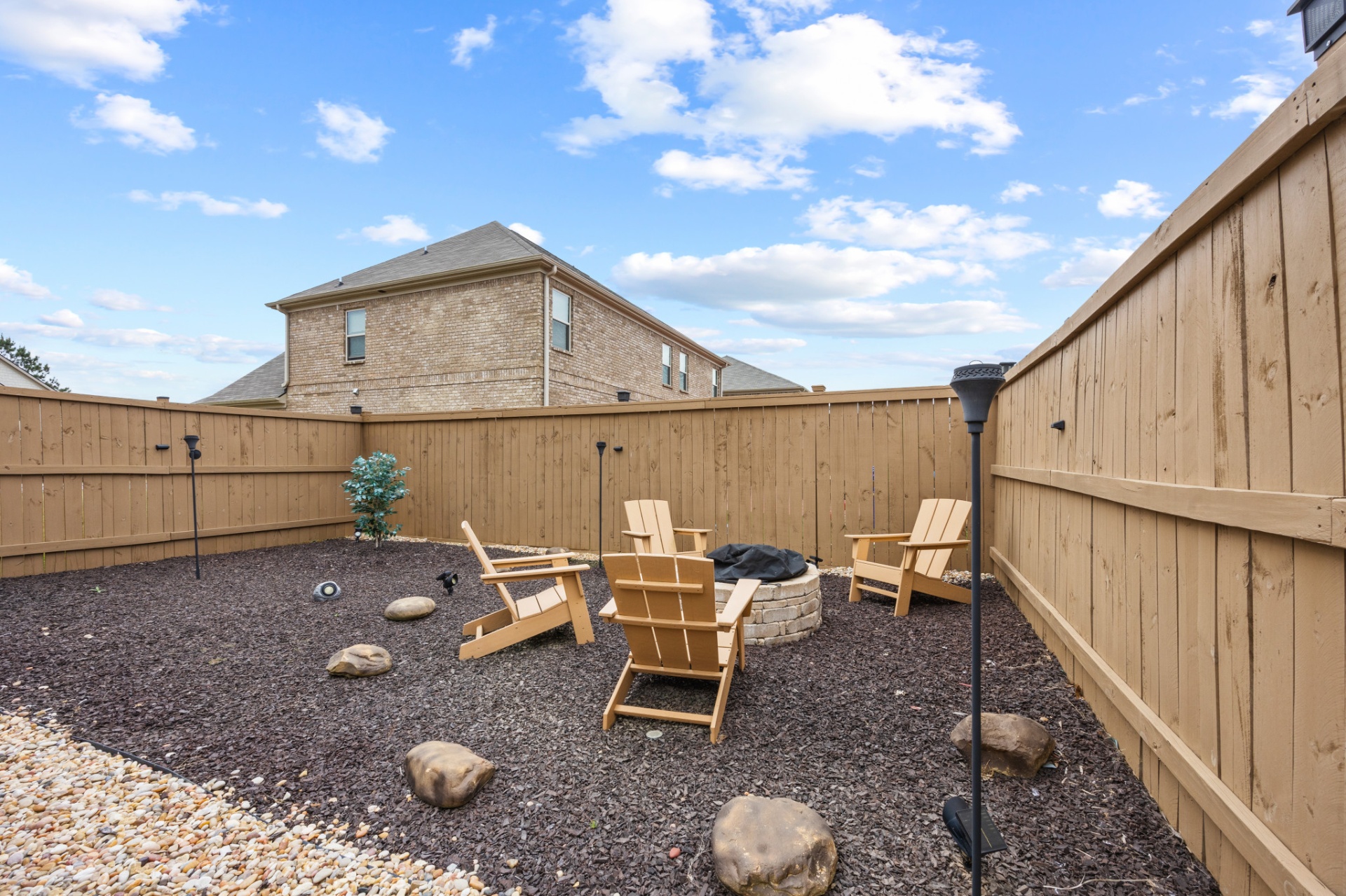 Private backyard firepit with adirondack chairs and tiki torches