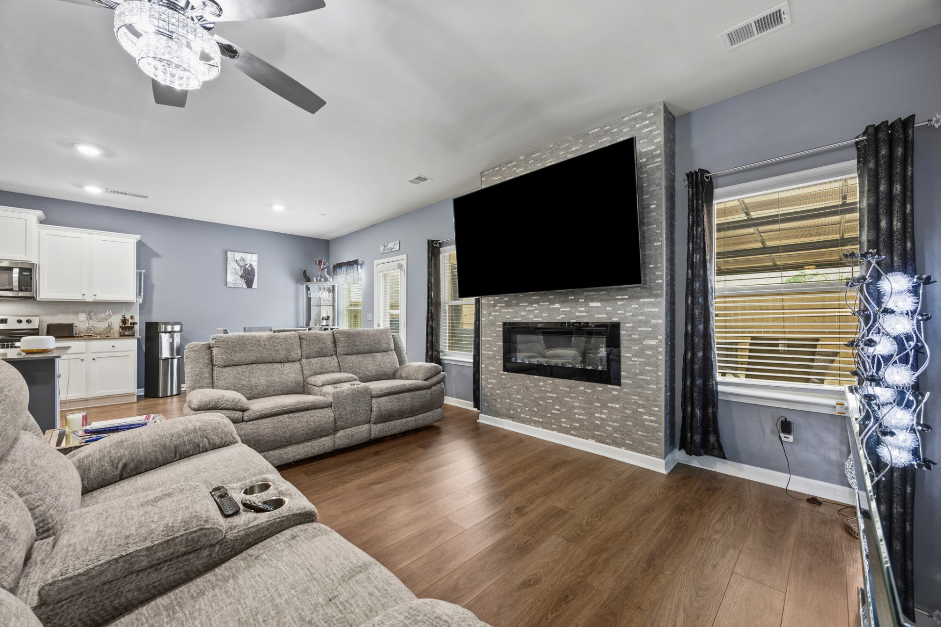 Living room with fireplace and mounted TV open to kitchen